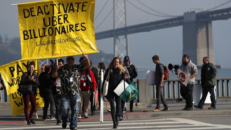Uber and Lyft drivers hold a sign reading “Deactivate Uber Billionaires” during a protest in San Francisco. 