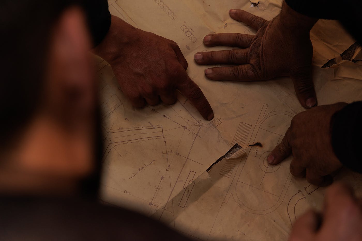 Groups of people, mostly made up of relatives and the local civilian population, examine the blueprints for the different buildings, searching for clues that might lead to hidden cells, bodies of prisoners, and proof of crimes such as torture, executions, or forced disappearances. 