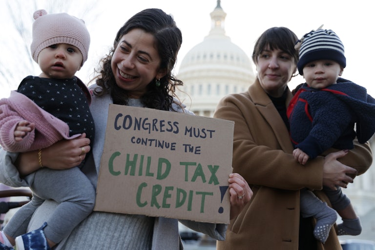 Two mothers hold their infant children and a sign in support of the child tax credit at a rally in Washington.
