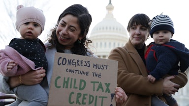 Two mothers hold their infant children and a sign in support of the child tax credit at a rally in Washington.