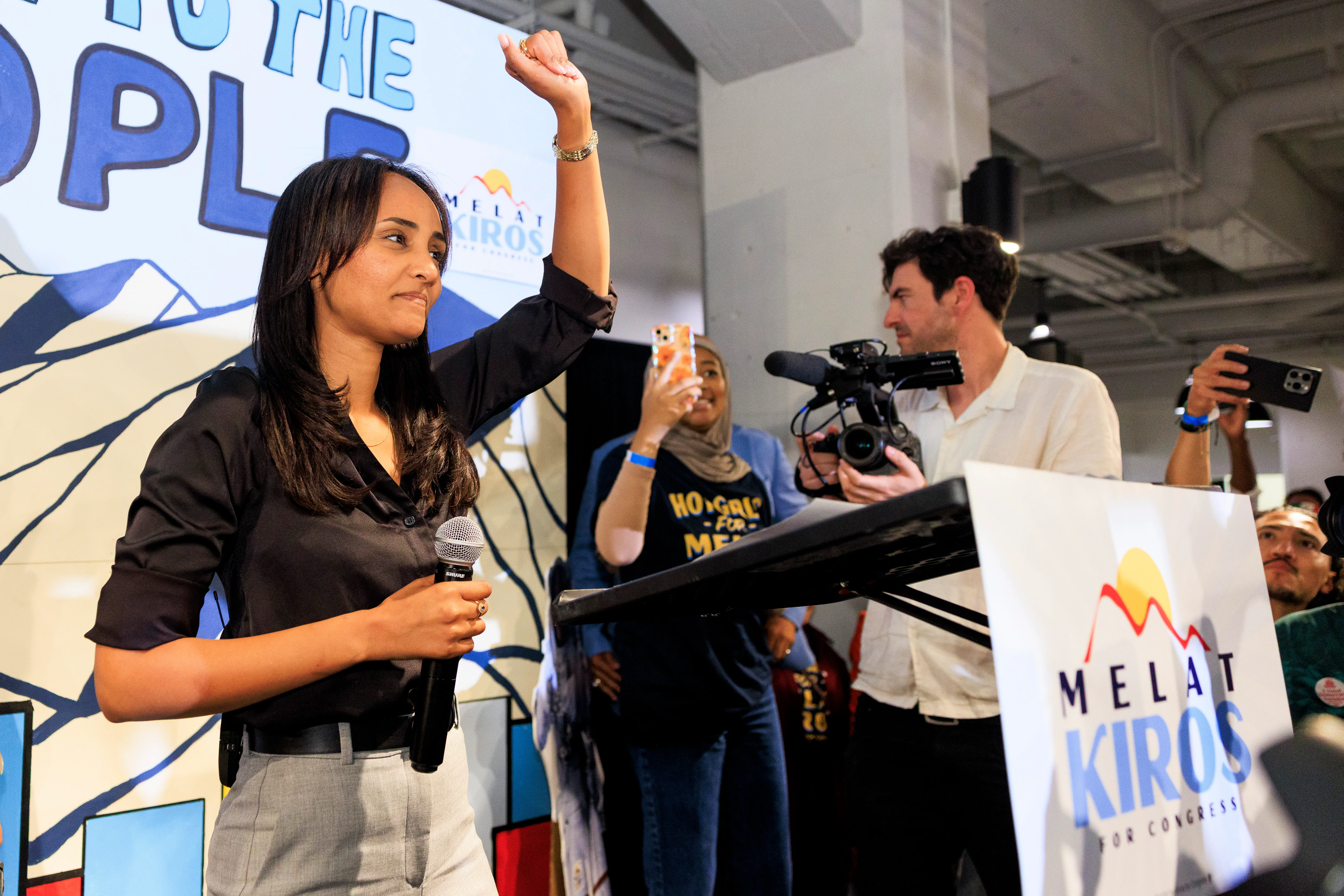 Democratic congressional candidate Melat Kiros speaks to supporters at an election-night watch party, her fist in the air.