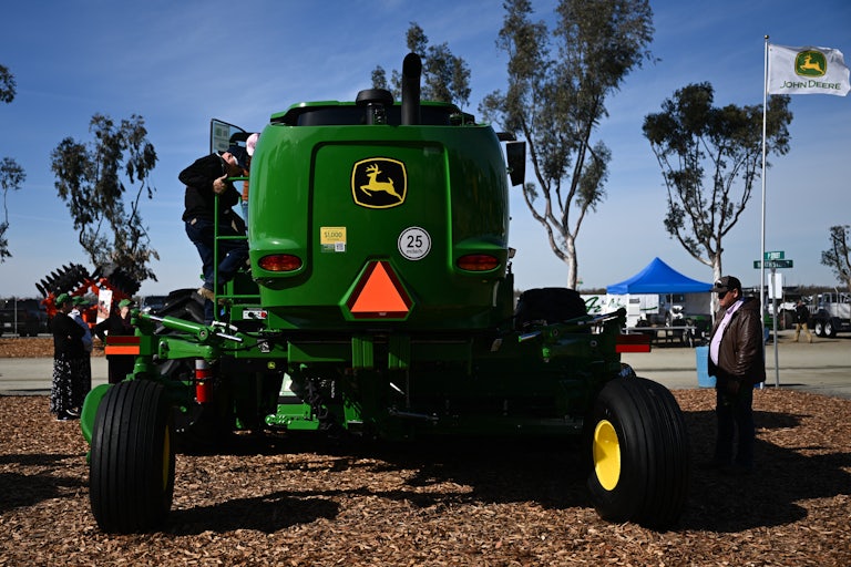 Two men stand near a John Deere tractor at the World Ag Expo in February.