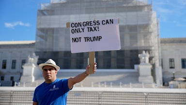 A person holds a sign that says, "Congress can only tax! Not Trump" outside the Supreme Court