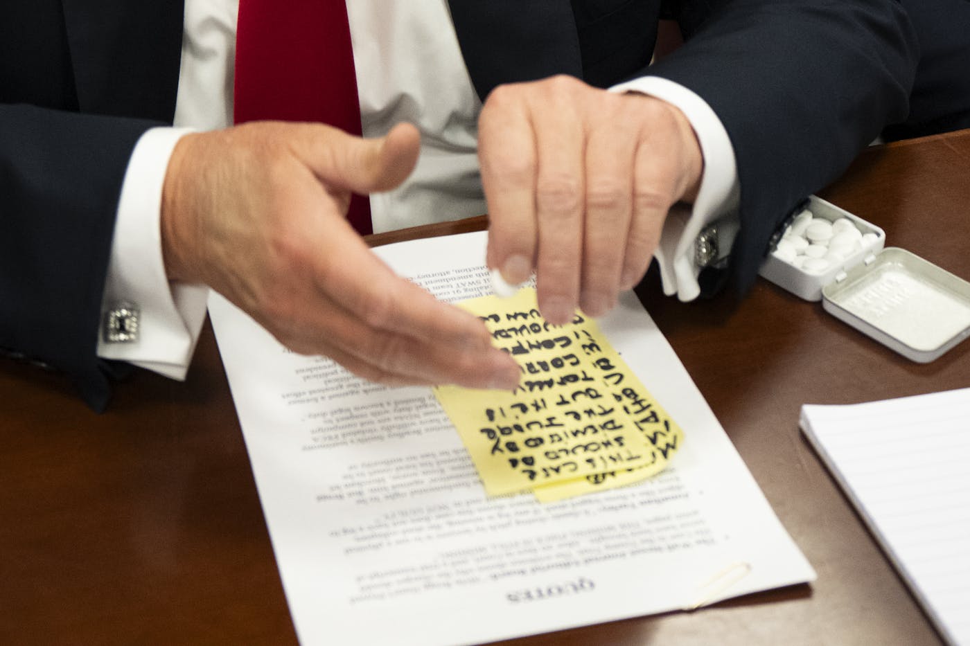 Closeup of Donald Trump's hands hovering above the sticky note