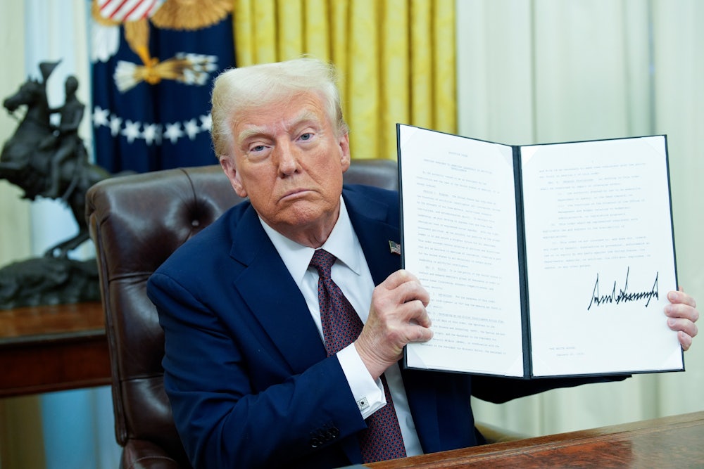 Donald Trump holds up an executive order he just signed in the Oval Office