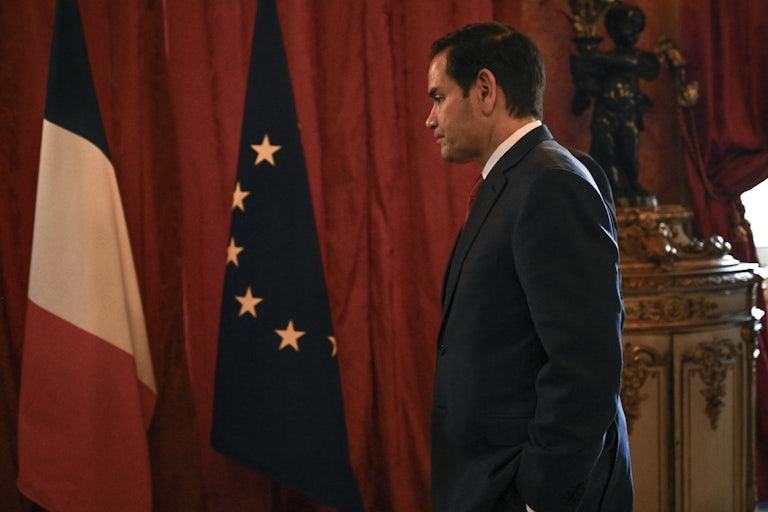 Secretary of State Marco Rubio stands next to a French flag and an EU flag