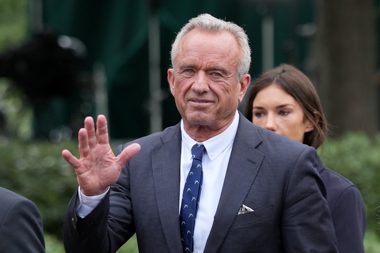 Robert F. Kennedy Jr. holds his hand up while walking outside