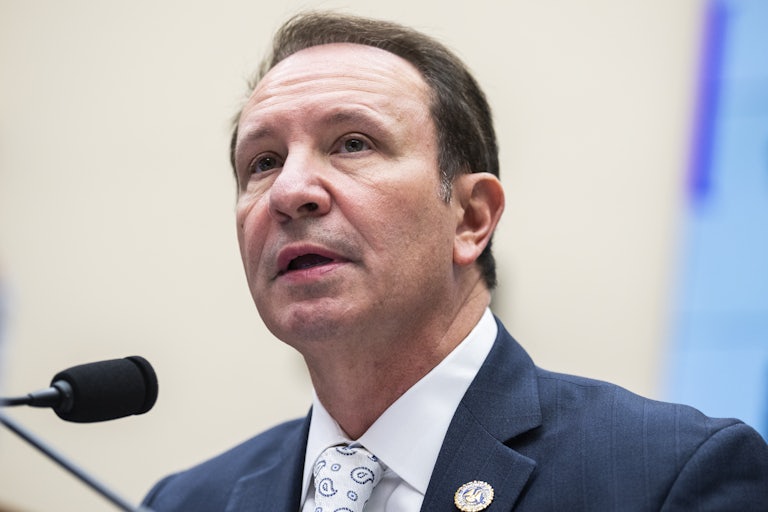 Louisiana Governor Jeff Landry has his mouth slightly ajar. A mic is before him. (He is in a congressional hearing.)