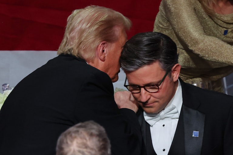 Donald Trump says something in Mike Johnson's ear. Others stand nearby.