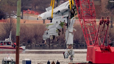 A large portion of the damaged plane is lifted from the Potomac River with a crane.