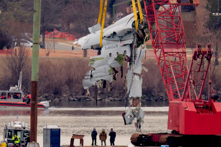 A large portion of the damaged plane is lifted from the Potomac River with a crane.