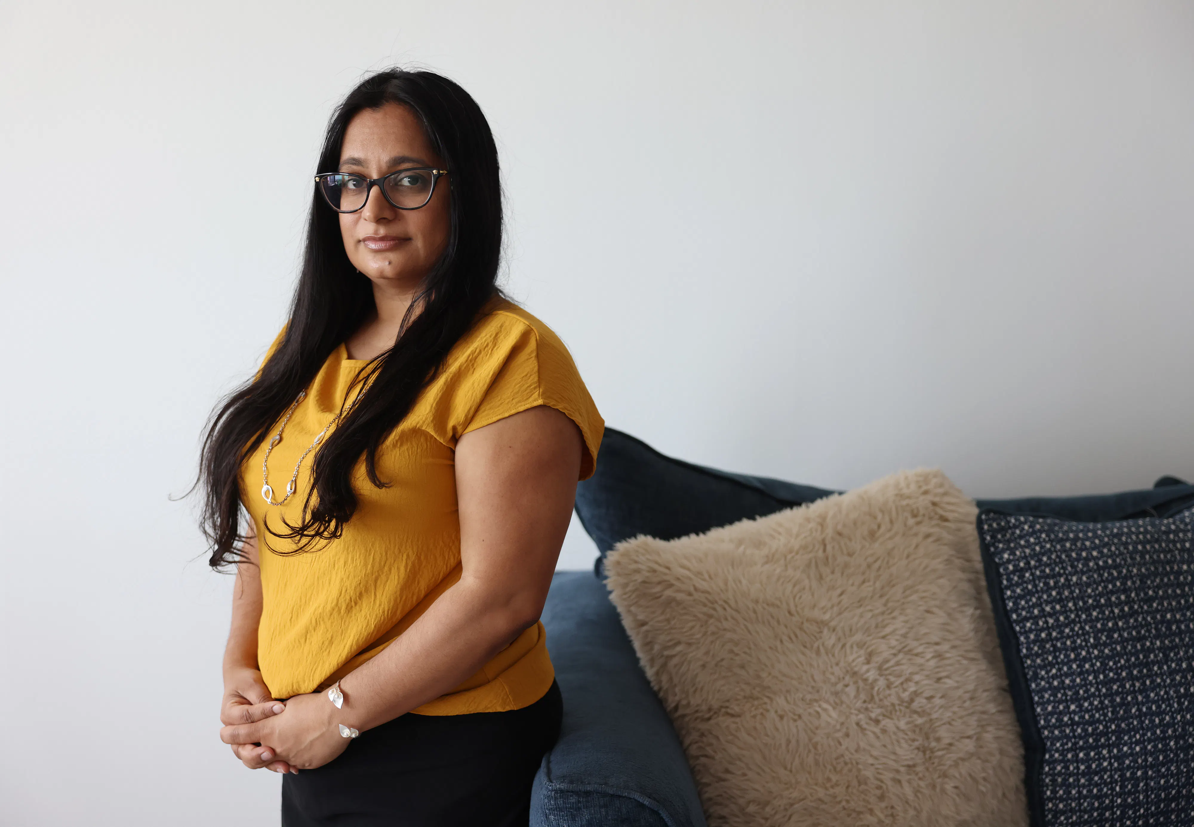 Judge Roopal Patel poses next to a couch with her hands folded in front of her