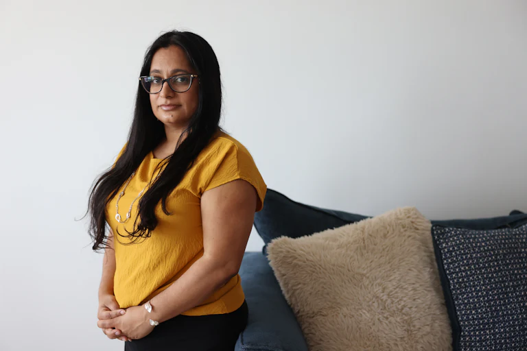 Judge Roopal Patel poses next to a couch with her hands folded in front of her