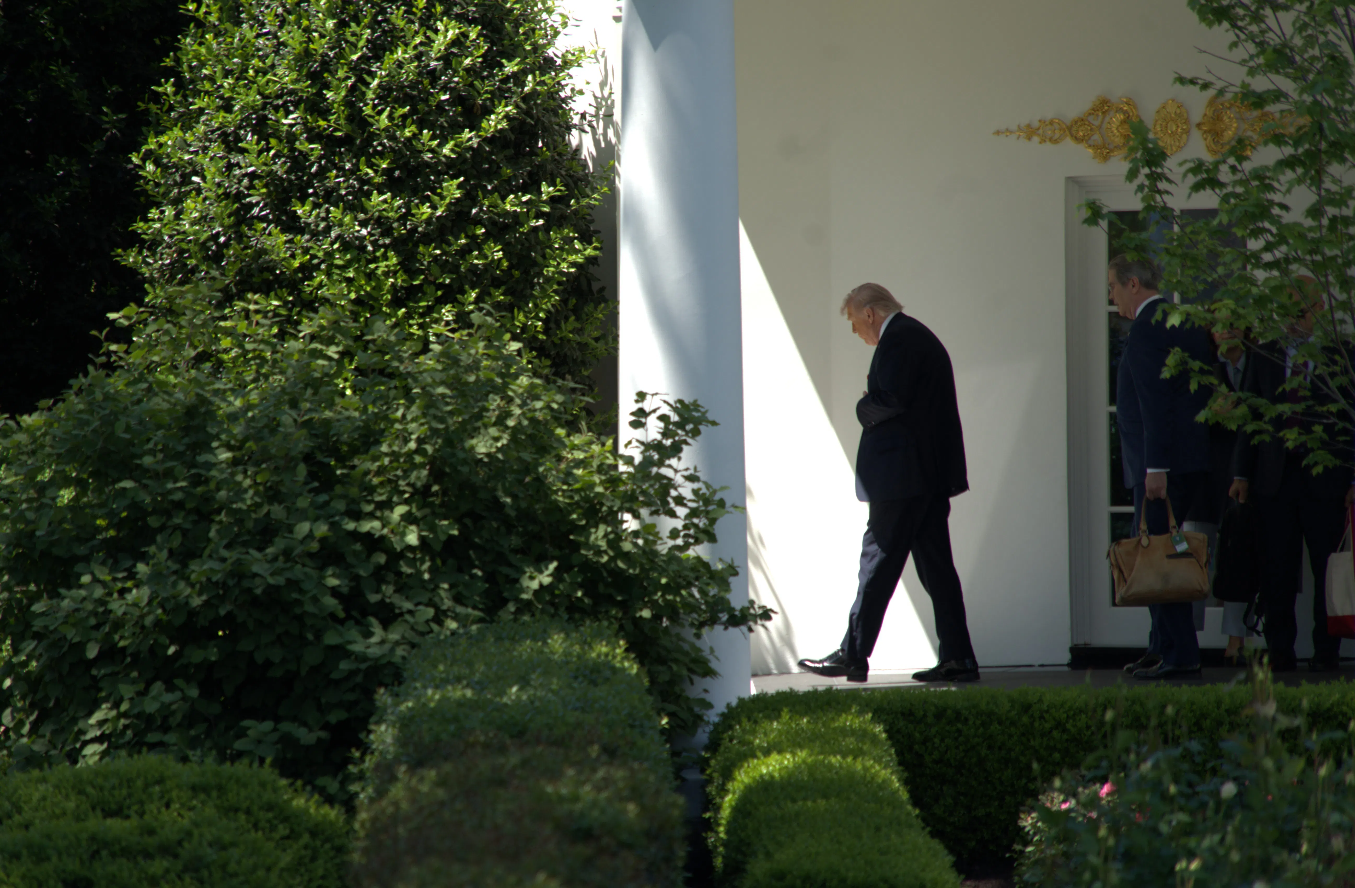 Donald Trump looks down while walking outside the White House
