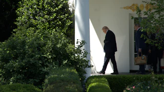 Donald Trump looks down while walking outside the White House
