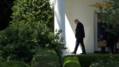 Donald Trump looks down while walking outside the White House