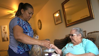 Lidia Vilorio, a home health aide, gives her patient Martina Negron her medicine and crackers for her tea.