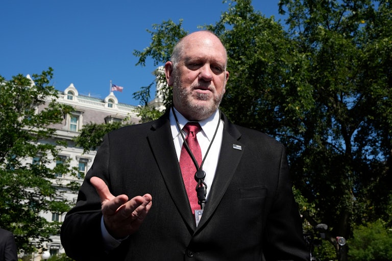 Tom Homan looks down and gestures while speaking to reporters outside the White House