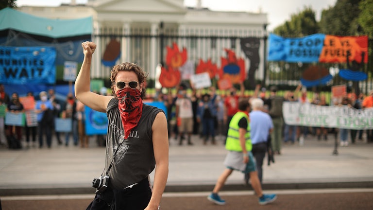 A climate protester raises a fist in front of the White House.