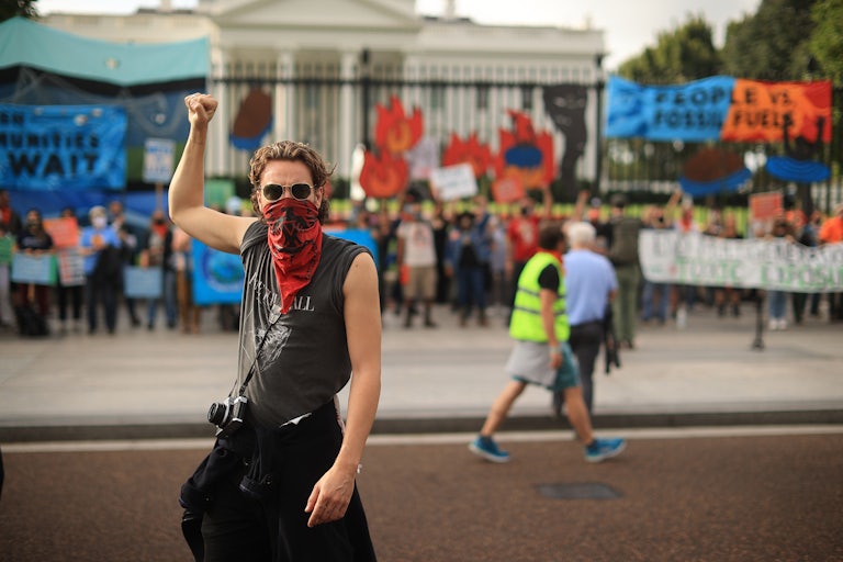 A climate protester raises a fist in front of the White House.