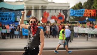 A climate protester raises a fist in front of the White House.