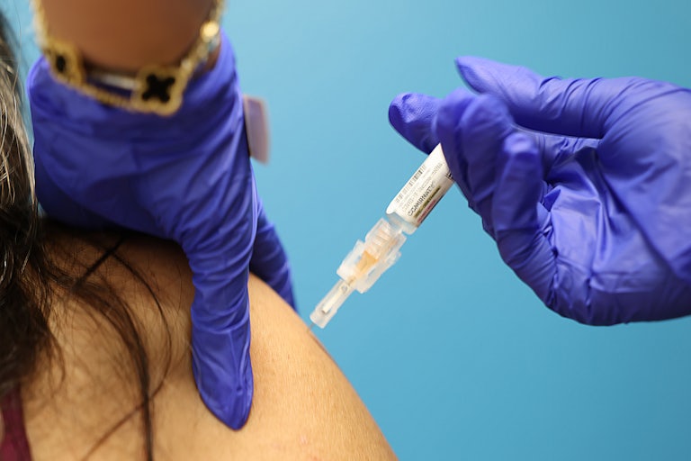 A nurse gives a COVID shot to a patient. (Both people are not pictured, only their hands and arm.)