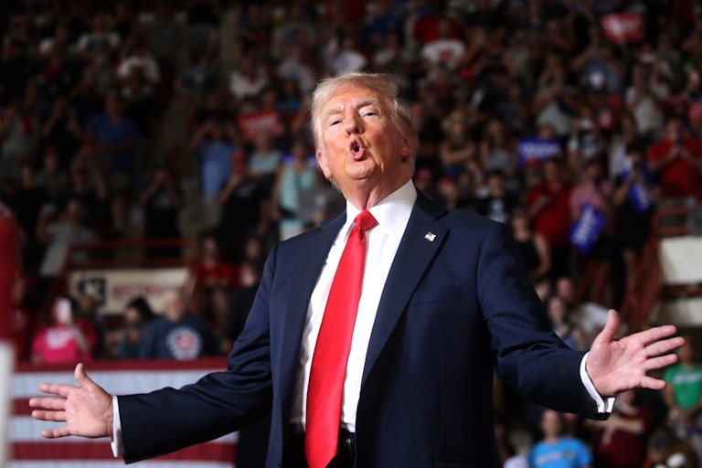 Donald Trump holds his arms out and makes a funny face at a campaign rally.