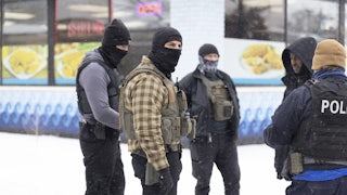 Masked ICE agents stand in the snow questioning a Black man.
