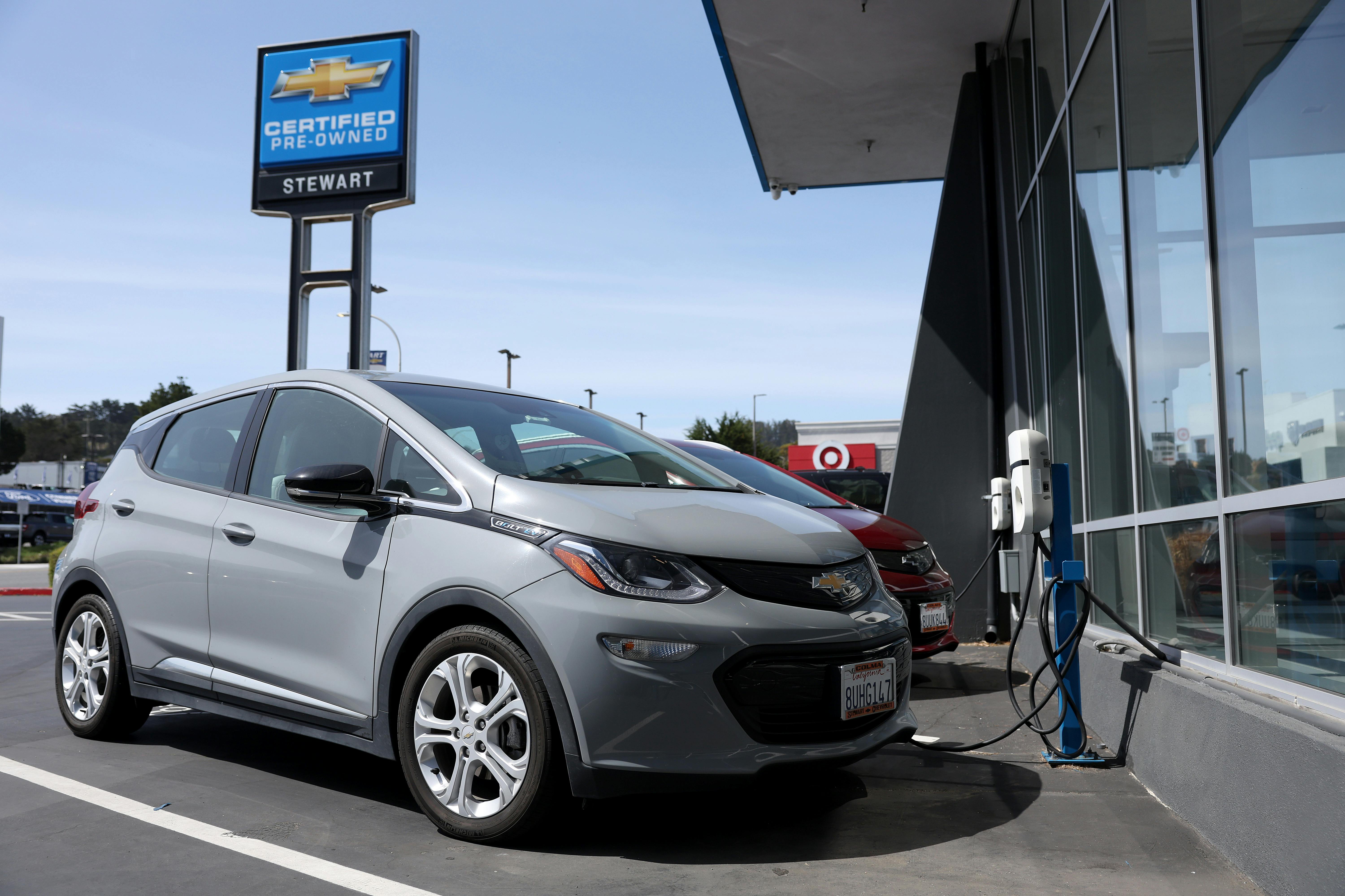 A Chevrolet Bolt sits in front of a charging station.