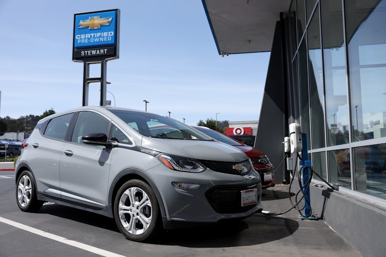 A Chevrolet Bolt sits in front of a charging station.