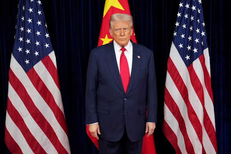 Donald Trump stands in front of two American flags and one Chinese flag