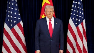 Donald Trump stands in front of two American flags and one Chinese flag