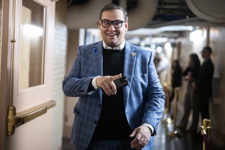 George Santos smiles and points