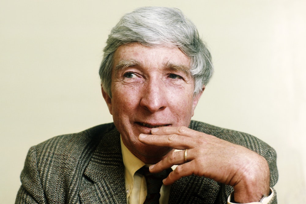 The author John Updike in a tweed suit with his hand over his mouth