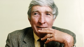 The author John Updike in a tweed suit with his hand over his mouth