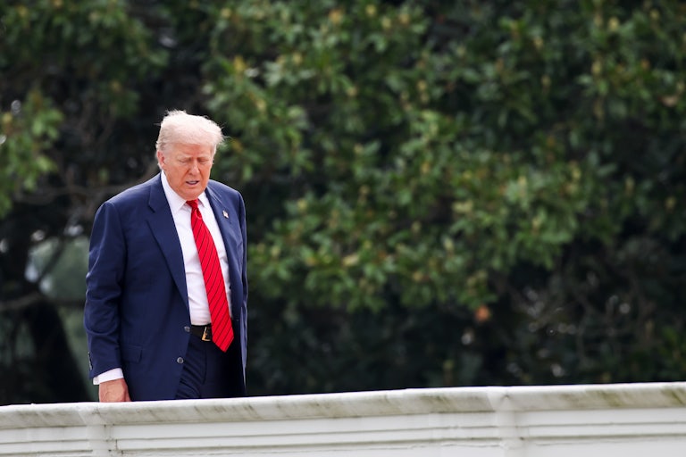 Donald Trump looks down while standing on the White House roof