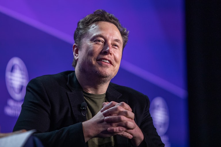 Elon Musk steeples his fingers as he appears at some conference panel