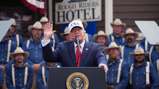 Donald Trump waves and looks up while speaking at a podium at an event at the Teddy Roosevelt Library