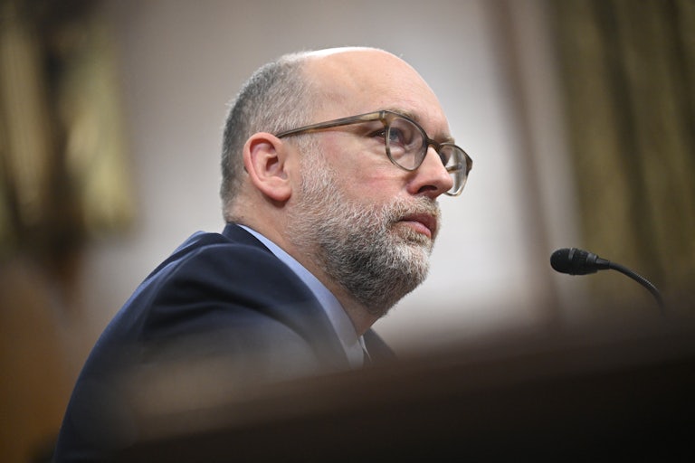 Russell Vought sits at a table during his Senate confirmation hearing