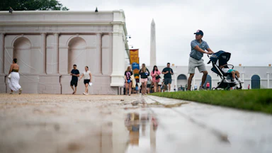 People walk in the rain at the Great American State Fair
