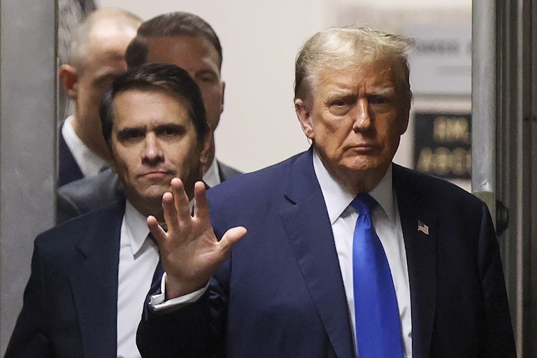 Donald Trump waves to the camera as his personal attorney Todd Blanche walks behind him in the courtroom.