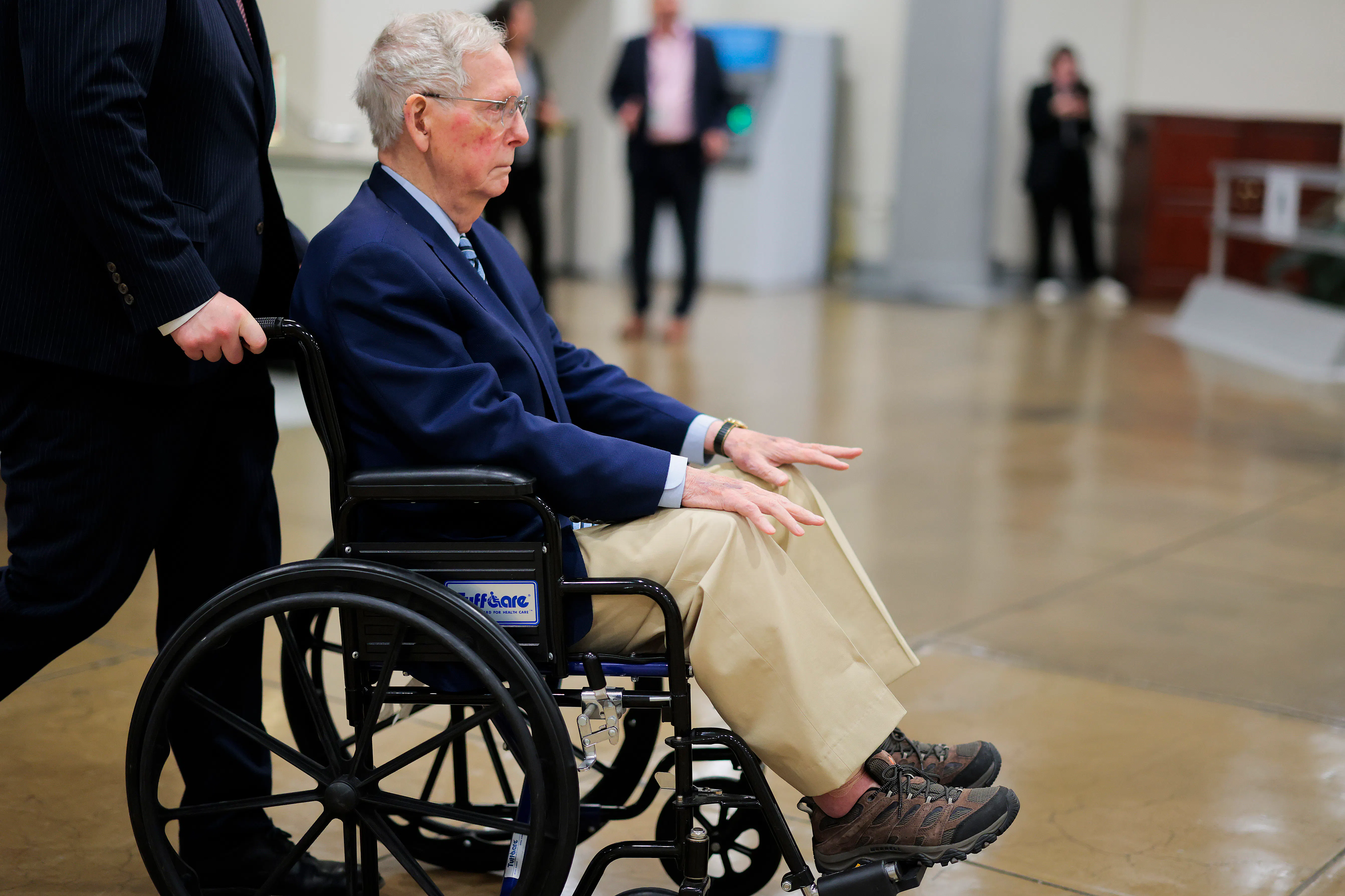 Mitch McConnel is pushed in a wheelchair through the Senate Subway.