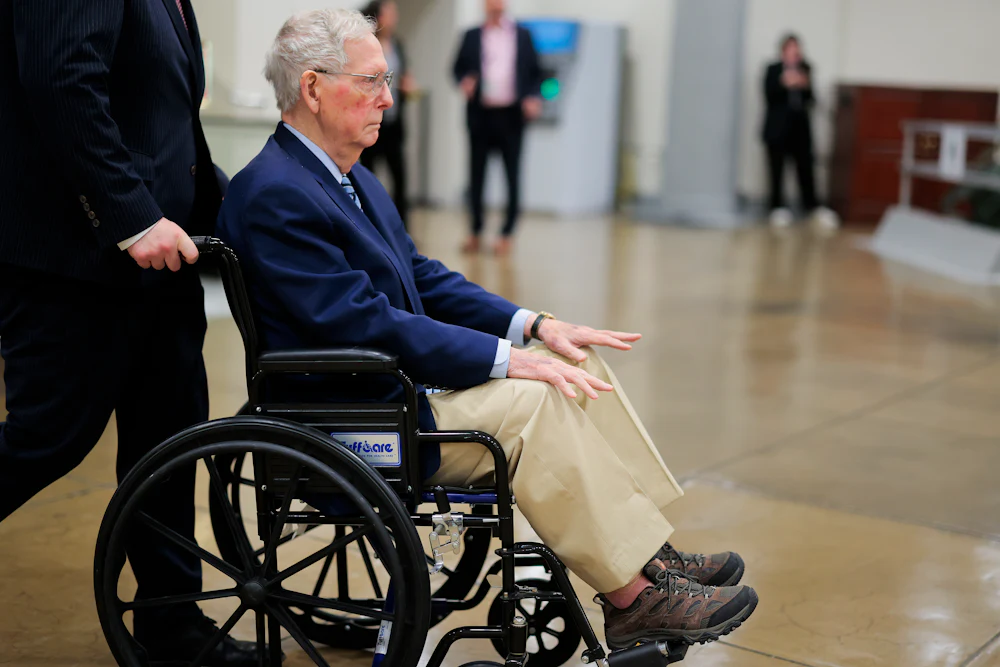 Mitch McConnel is pushed in a wheelchair through the Senate Subway.