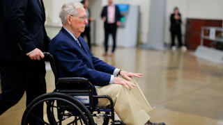Mitch McConnel is pushed in a wheelchair through the Senate Subway.