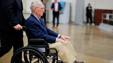 Mitch McConnel is pushed in a wheelchair through the Senate Subway.