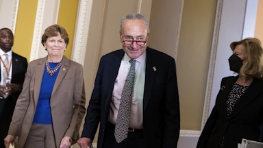 Senate Majority Leader Charles Schumer smiles as Senator Jeanne Shaheen in the Capitol walks by his side.