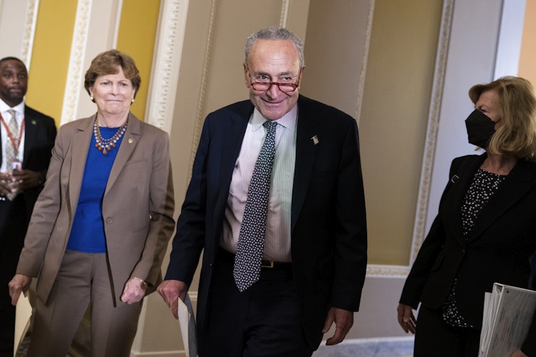 Senate Majority Leader Charles Schumer smiles as Senator Jeanne Shaheen in the Capitol walks by his side.