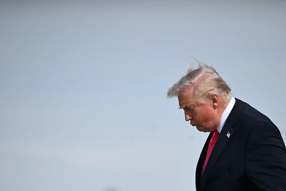 Donald Trump, stooped forward, stares down at the ground
