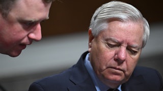 Lindsey Graham looks down while speaking with an aide during a Senate hearing