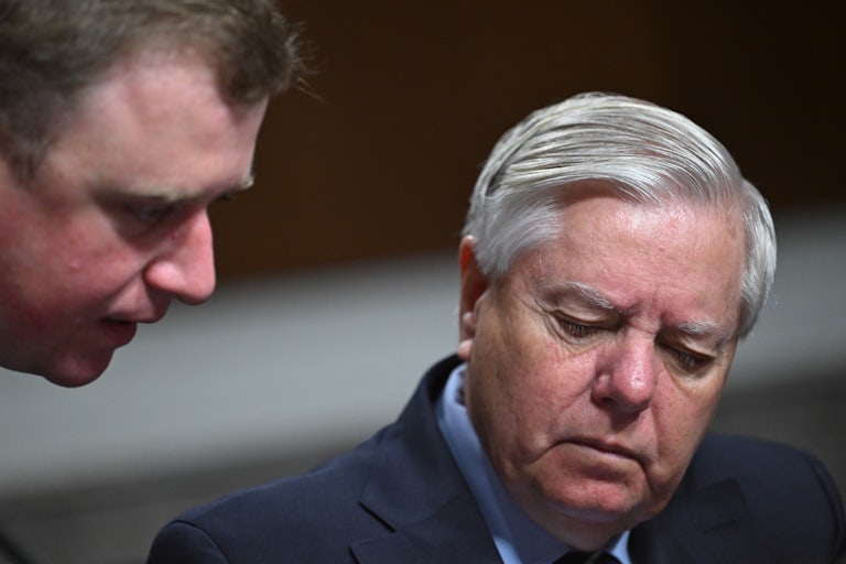 Lindsey Graham looks down while speaking with an aide during a Senate hearing